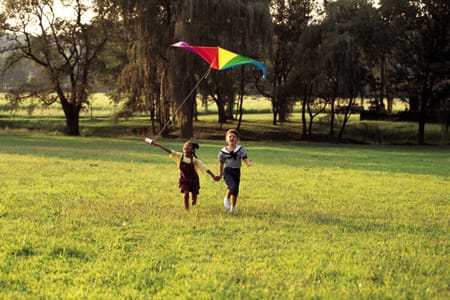 two kids playing with kite in field